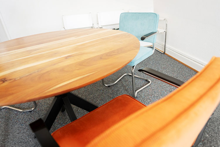 Arztzimmer - runder Holztisch und zwei bunte Stühle